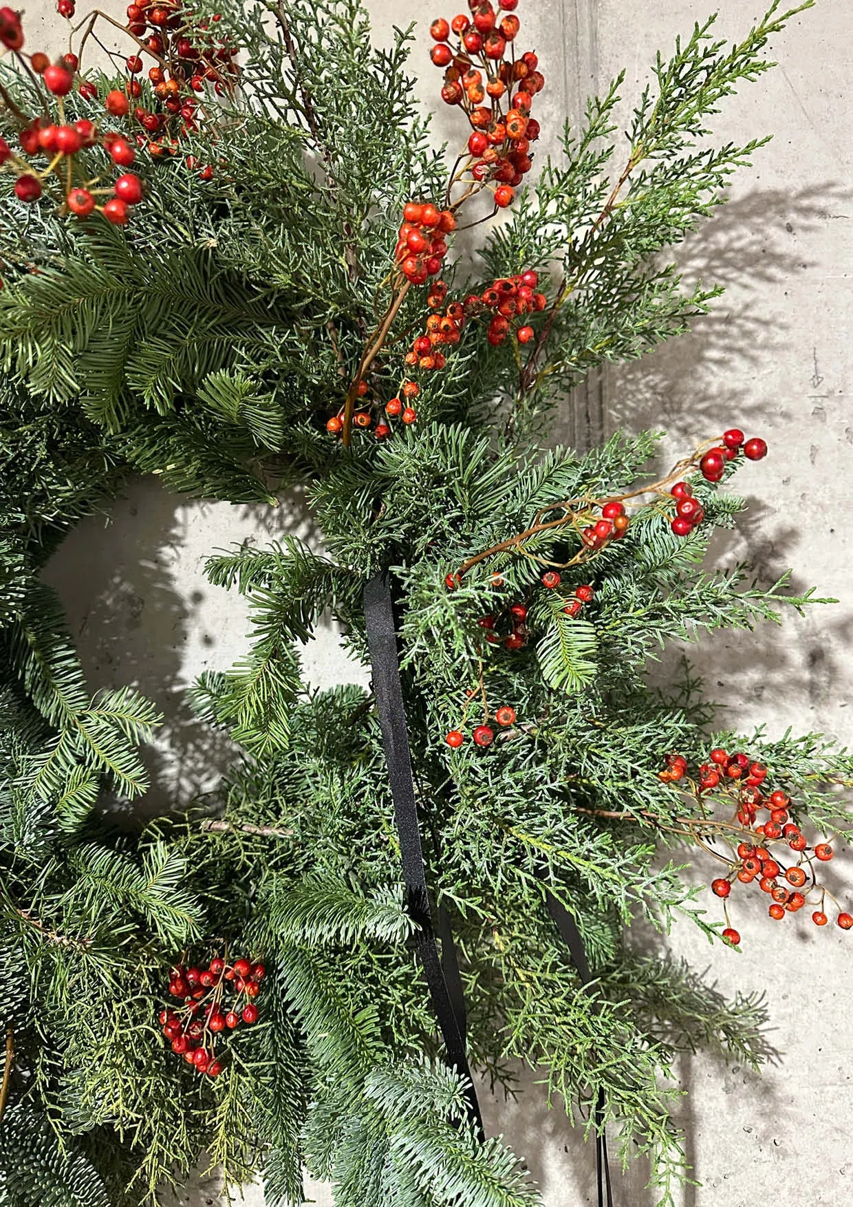 Christmas wreath made of fir branches and black ribbon