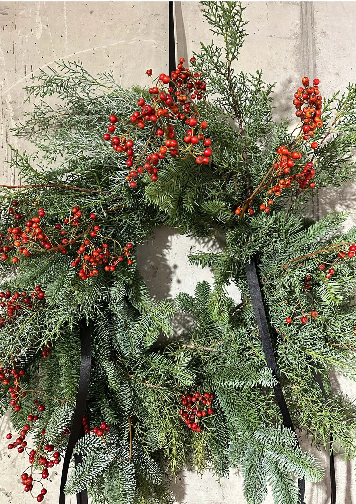 Christmas wreath made of fir branches and black ribbon